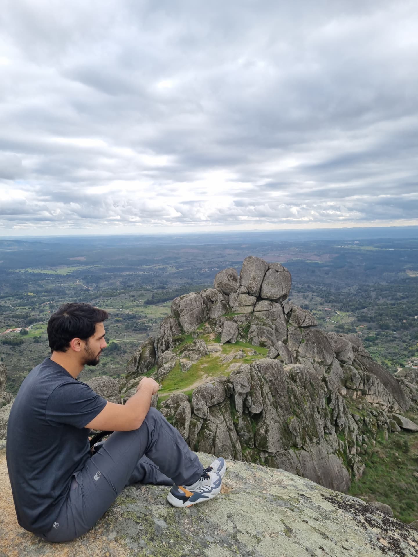 Viajante sentado observando a paisagem montanhosa a partir do alto de Monsanto