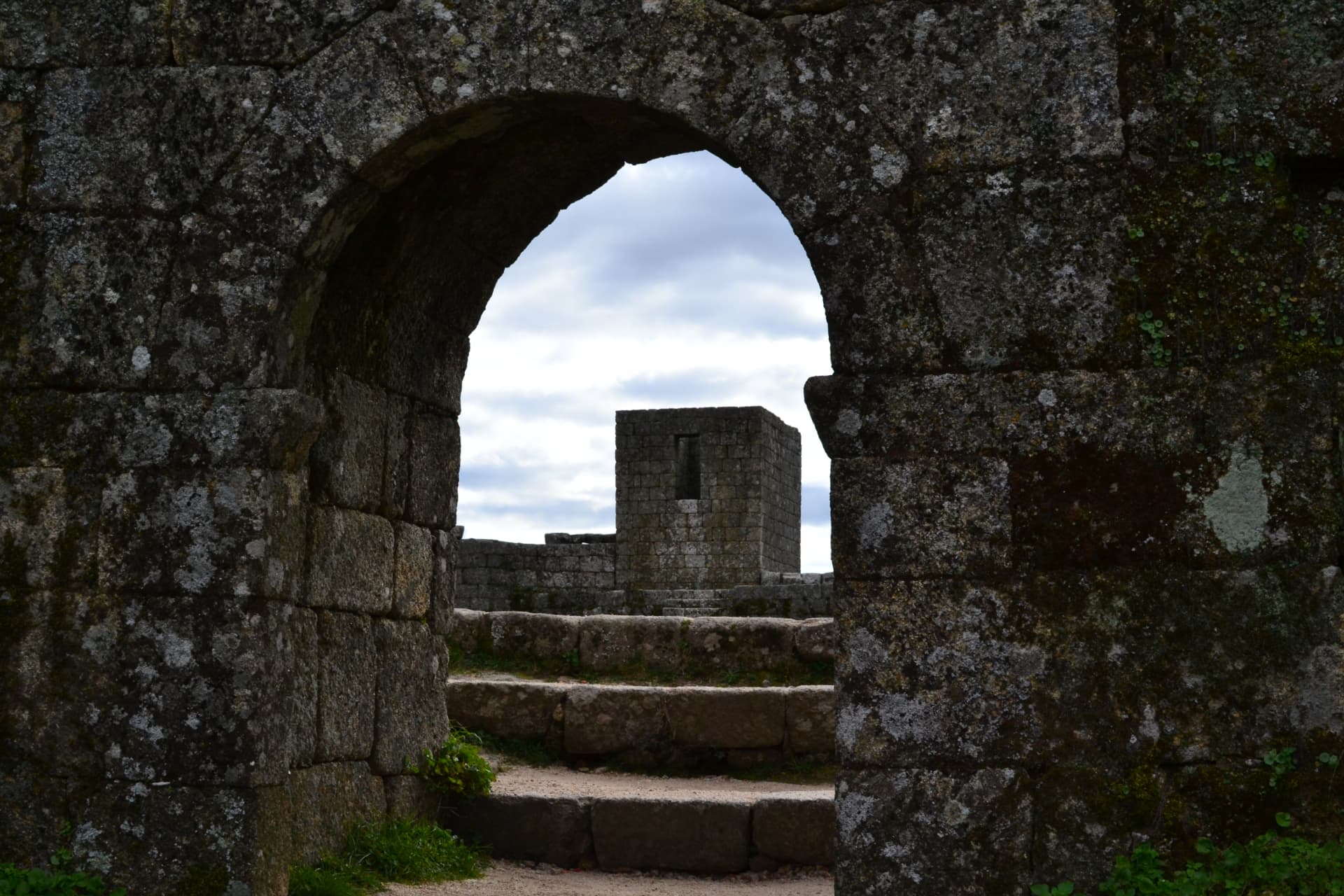 Vista através de um arco de pedra para outra construção de granito em Monsanto