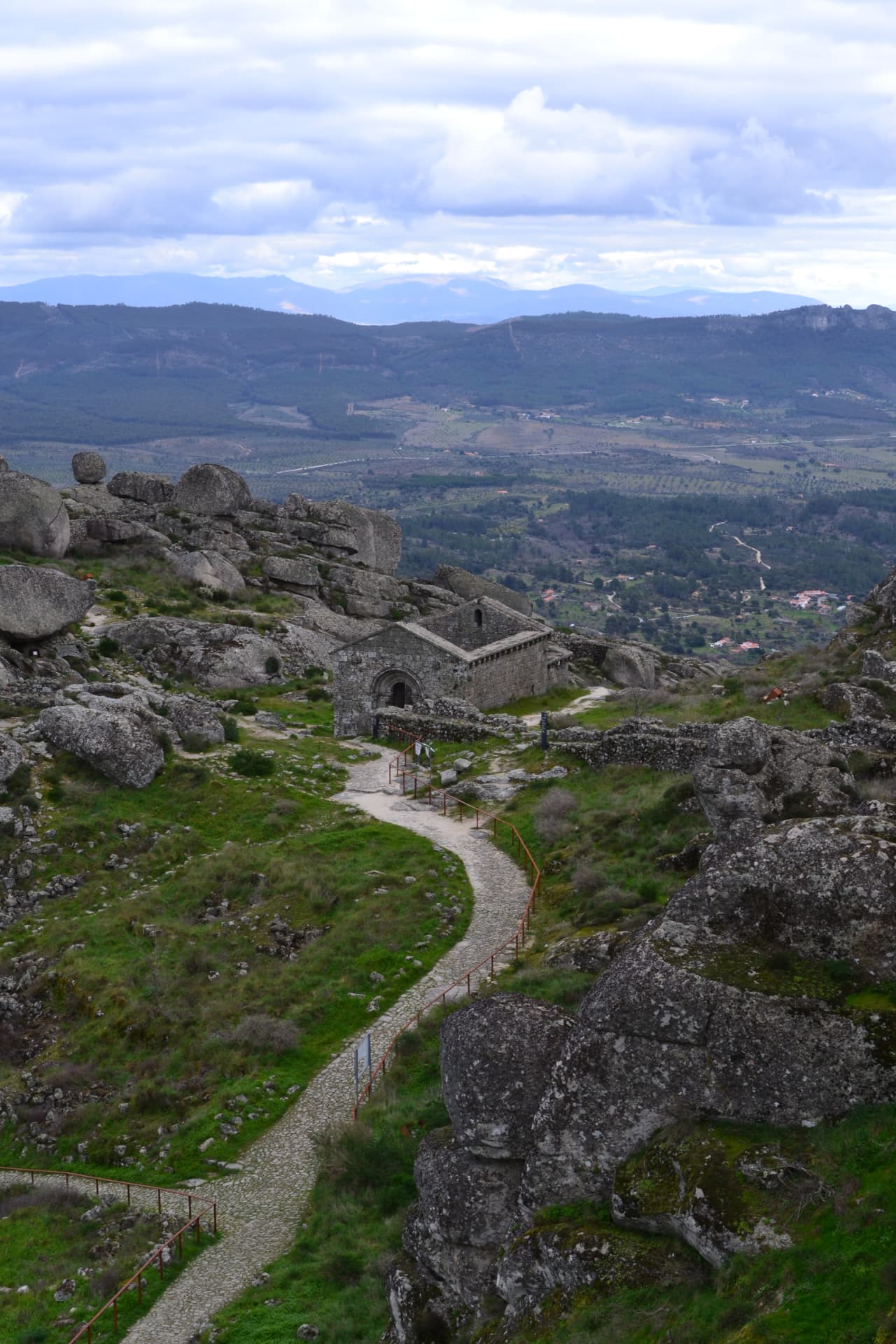 Caminho sinuoso de pedra levando às ruínas do castelo numa paisagem árida