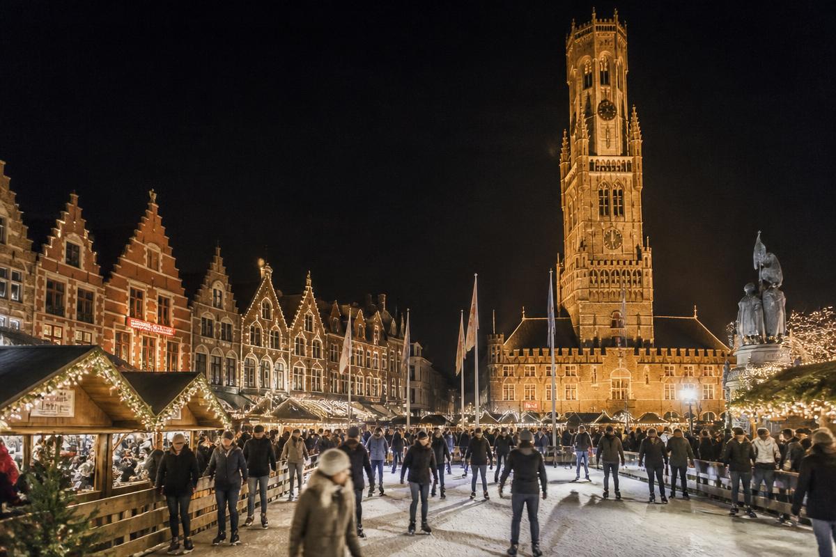Praça Markt de Bruges com o campanário medieval e o mercado de Natal iluminado
